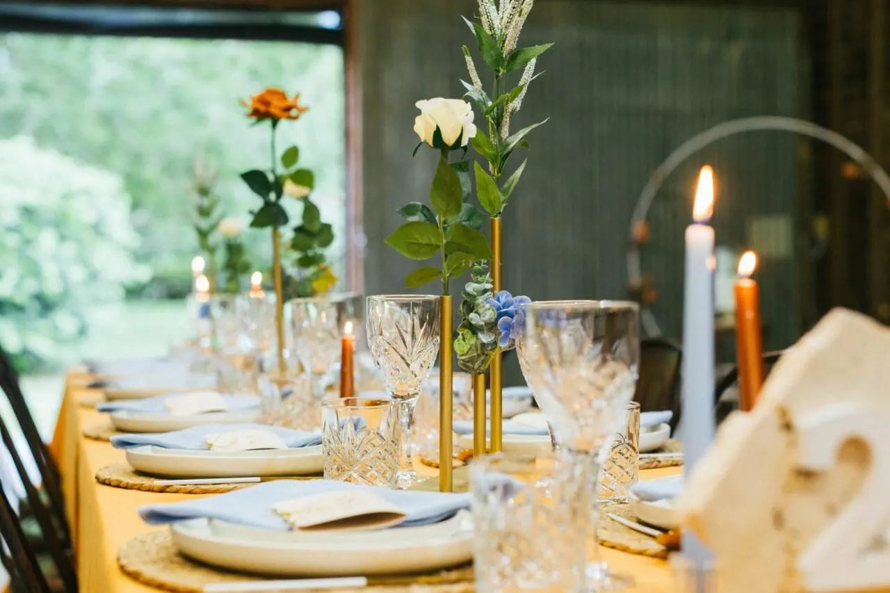 A styled celebration table inside The Barn, with candles, flowers and place settings